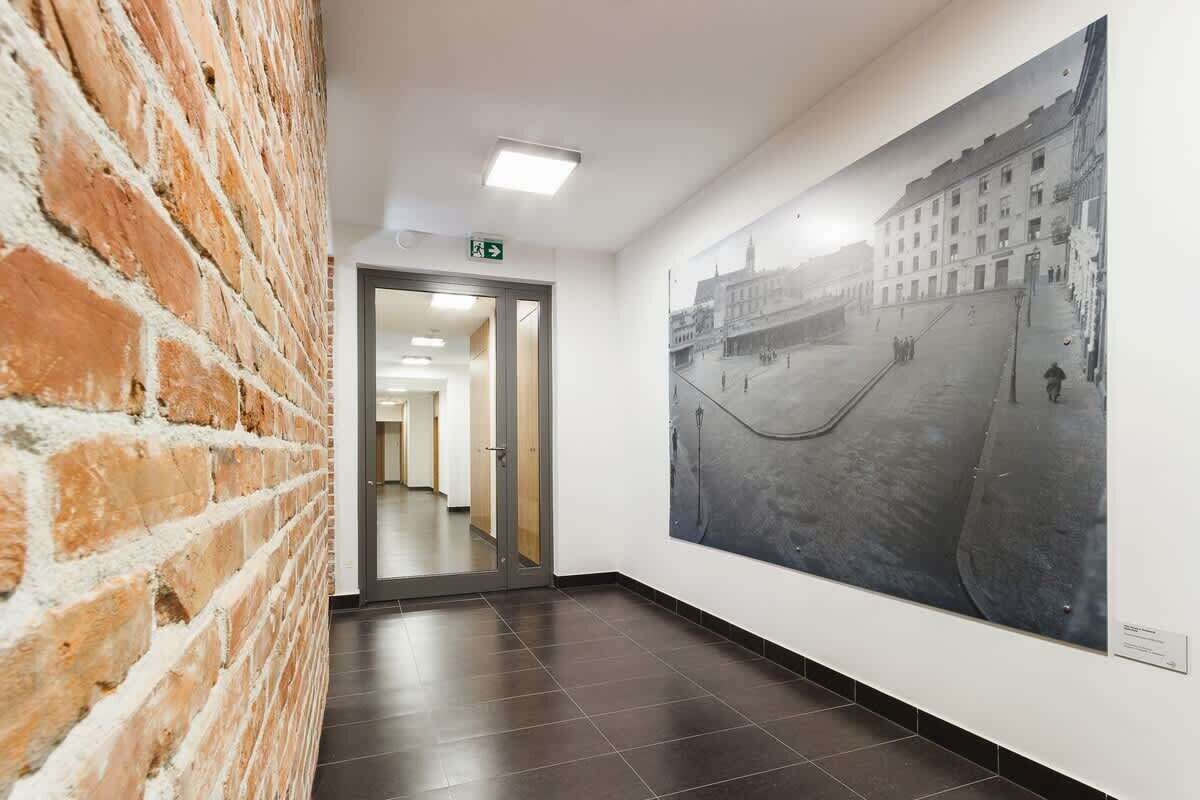 Un corridoio con una parete in mattoni, una porta in vetro che dà su un'altra stanza e un grande murale storico sulla parete.