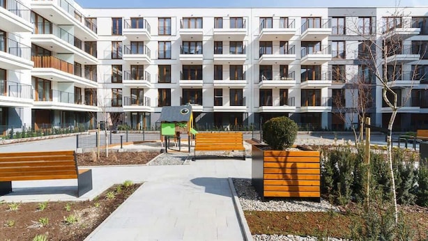 A modern apartment building with multiple balconies, a central courtyard with benches, and a small playground area. - Stylish Apartment near the Station | Parking | Balcony (Kraków)