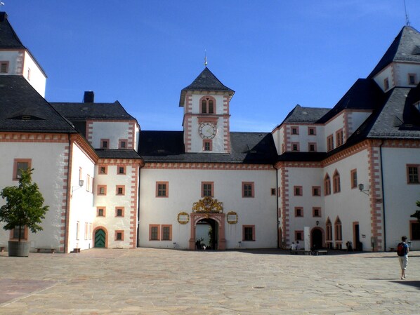 A historic building with a central clock tower, symmetrical architecture, and a courtyard.
