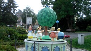 Un jardin agrémenté d’une fontaine circulaire ornée de personnages de dessins animés et d’une grande sculpture en forme d’arbre.