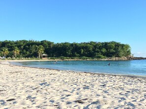 Ranta lähistöllä, aurinkotuoleja, aurinkovarjoja, rantapyyhkeitä