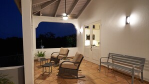 An outdoor patio with a ceiling fan, a bench, and two rocking chairs.