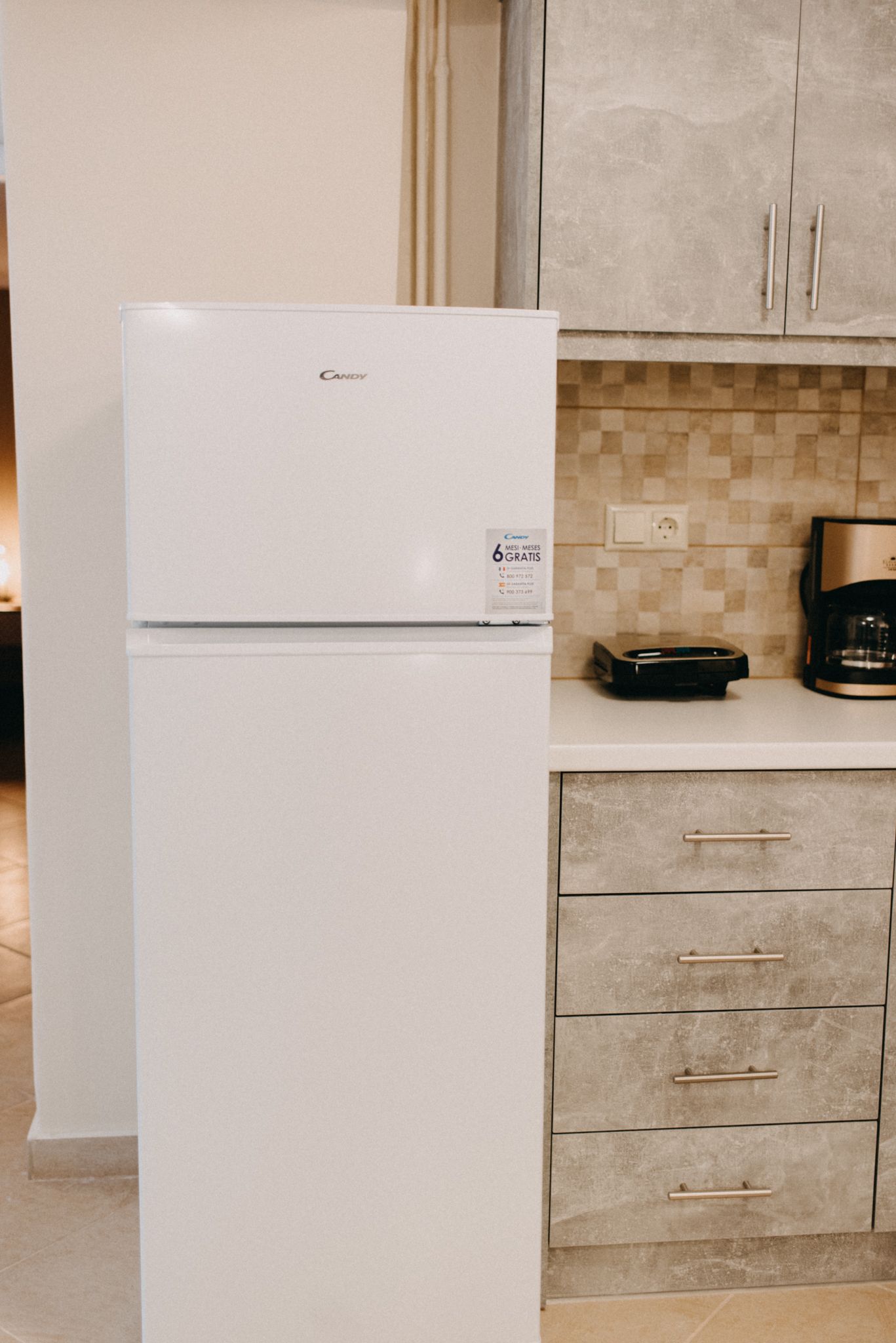 Una cocina con un refrigerador blanco, una cafetera y un microondas en la encimera.