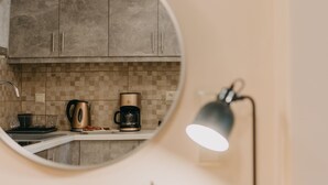 A kitchen with a round mirror, a coffee maker, and a lamp on a wooden countertop. - Best House Central Luxury Apartment (Patras)