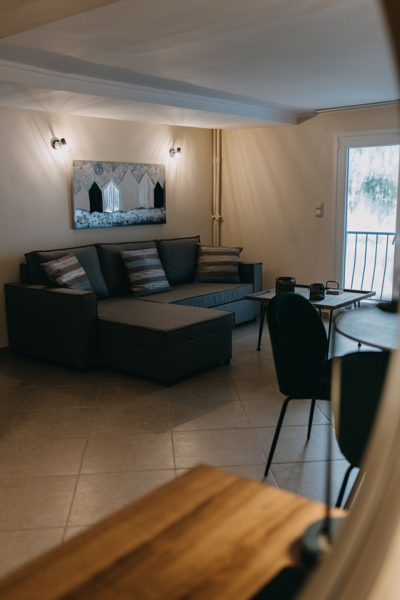 A modern living room with a sectional sofa, a dining table, and a painting on the wall.
