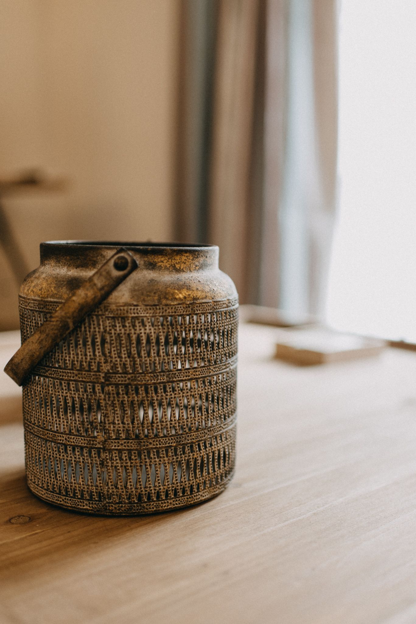 A rustic, woven basket with a handle on a wooden surface.