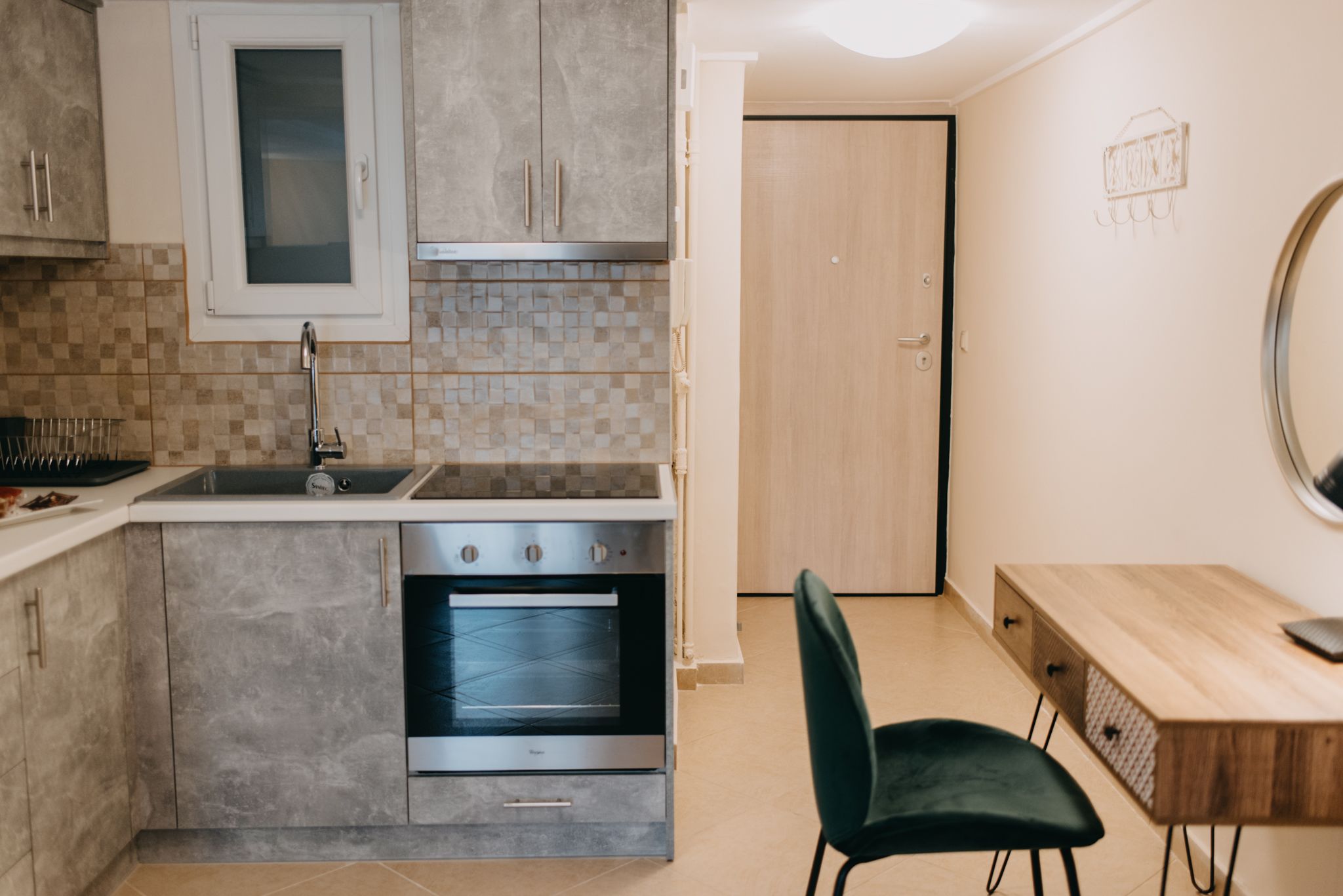 Une cuisine moderne dotée d’un four encastré, d’un évier et d’un coin repas avec une chaise et une table en bois.