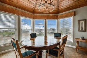 A dining room with a round table, four chairs, and a chandelier.