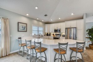 A modern kitchen with a central island, bar stools, and stainless steel appliances.