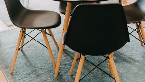 Un comedor con una mesa redonda, sillas negras y una pequeña planta en maceta.