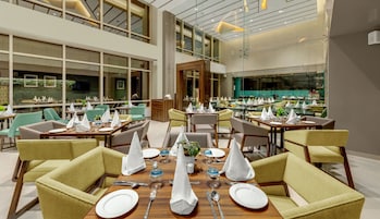 Un comedor moderno con varias mesas dispuestas para comensales, con una combinación de sillas y una mesa central.
