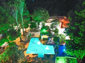 Vista aérea de un resort con piscina, zona de descanso y vegetación circundante.