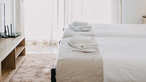 A hotel room with a bed, a bedside table, a TV, and an air conditioning unit. - Best House Town View Apartment (Patras)