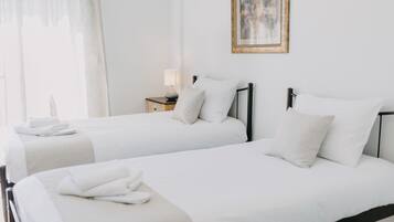 A hotel room with two beds, a nightstand with a lamp, and a framed picture on the wall.