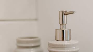 Two white ceramic jars with pump dispensers on a white shelf.