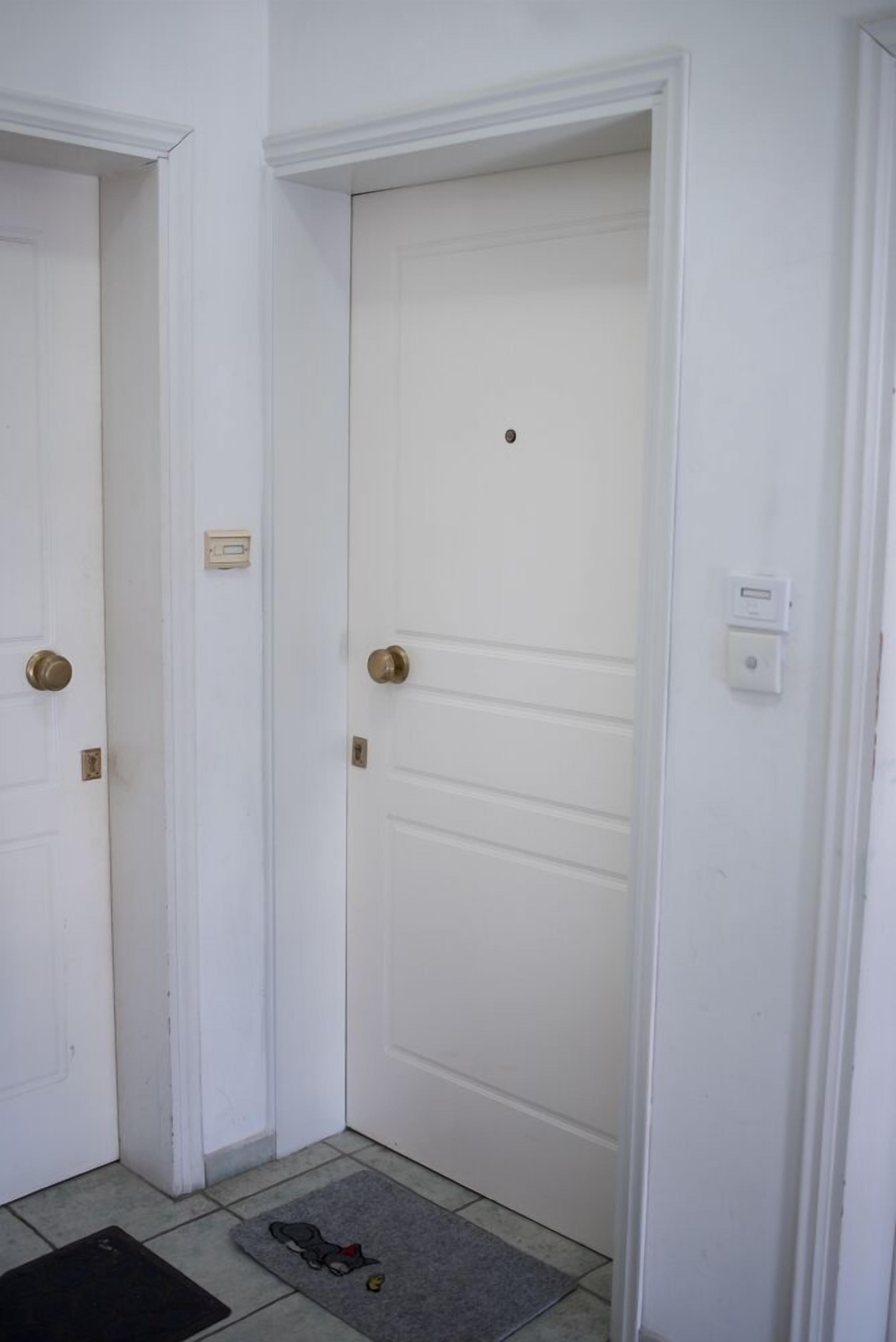 A white door with a brass handle and a small control panel above it.