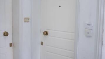 A white door with a brass handle and a small control panel above it.