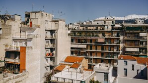 A multi-story residential building with balconies, a red door, and a mountainous backdrop.