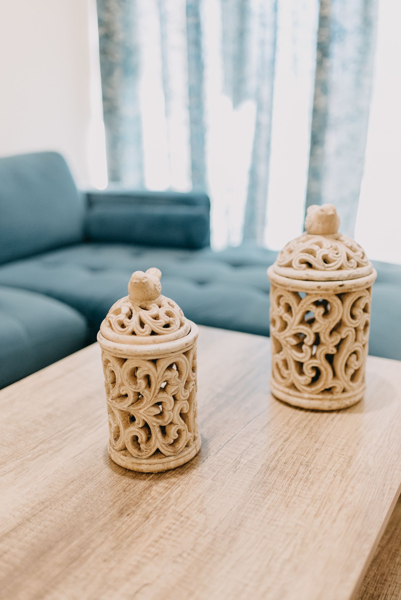 Two intricately carved ceramic containers on a wooden table.
