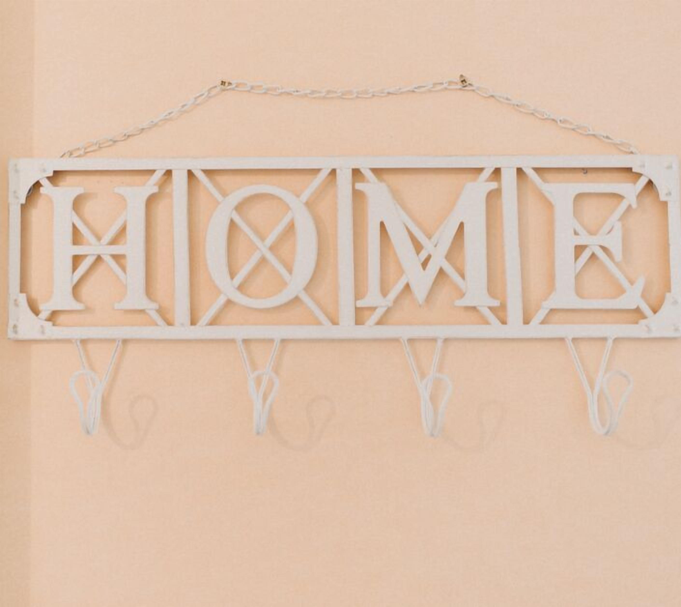A white metal sign with the word "HOME" in large letters, hanging on a wall with a chain.