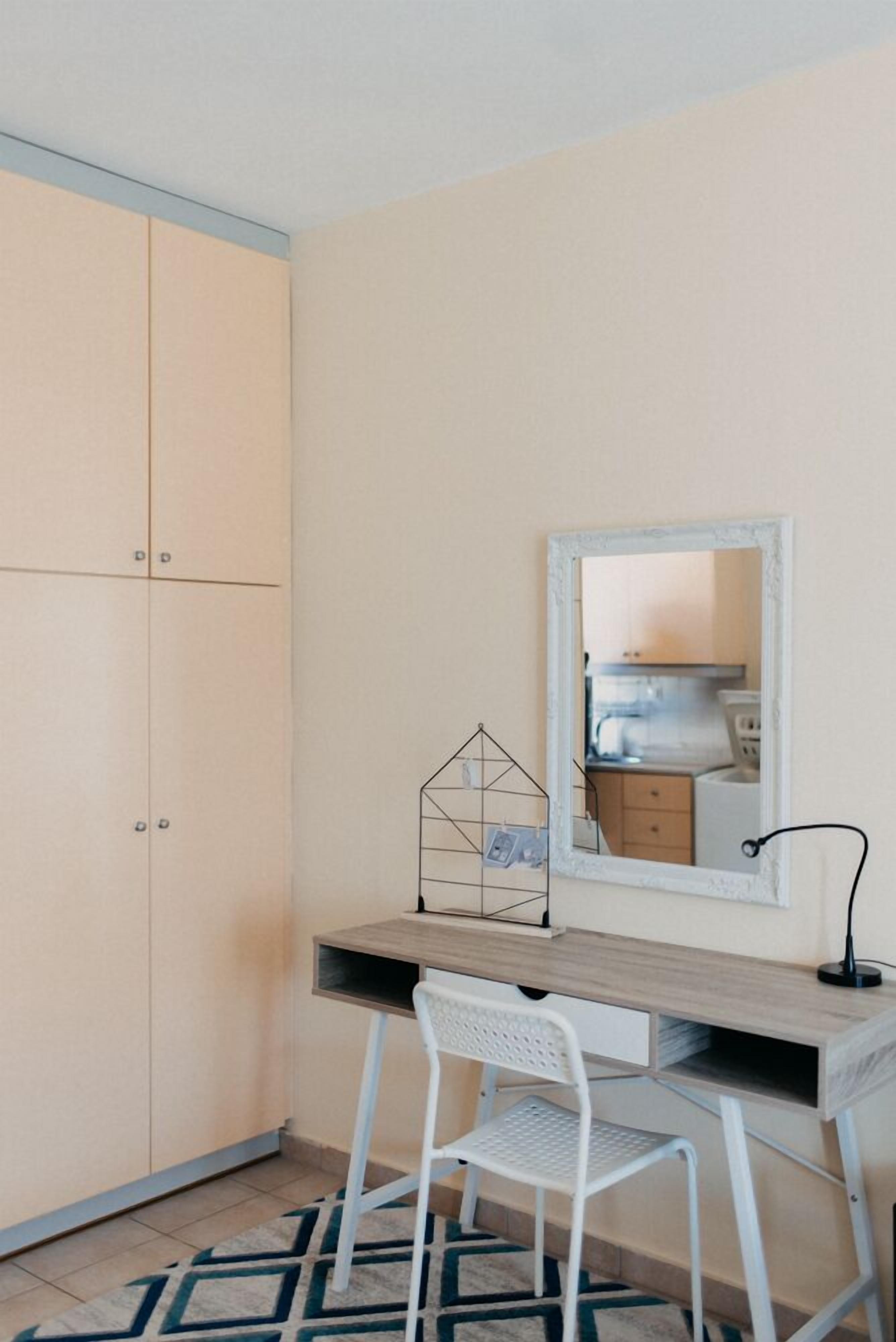 A compact room with a desk, chair, and wardrobe.