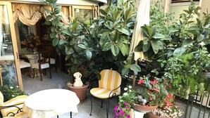 A patio area with a table and chairs, surrounded by potted plants and flowers. - Hotel Claridge (Rapallo)