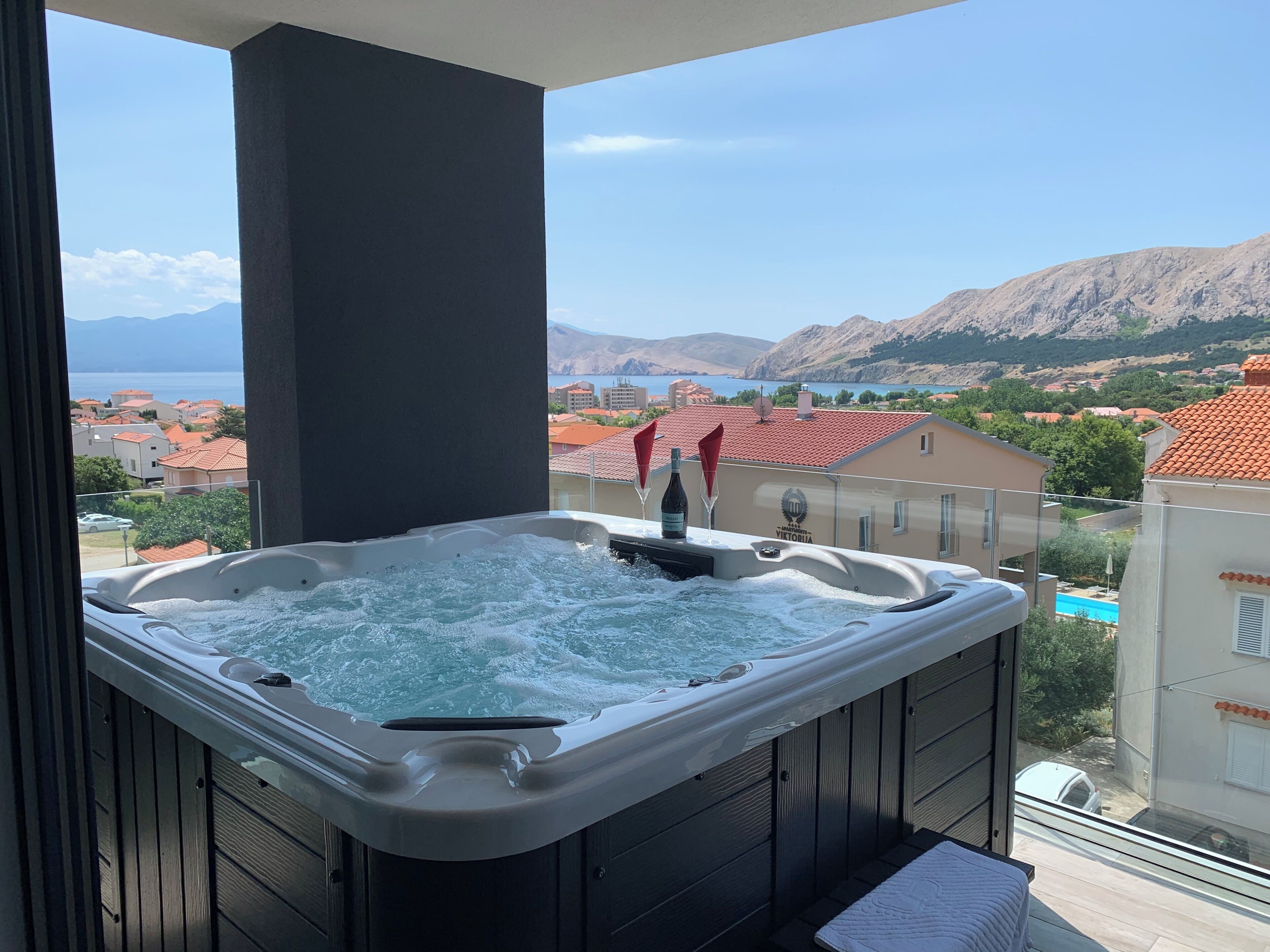 A hot tub with a view of a coastal town and mountains.