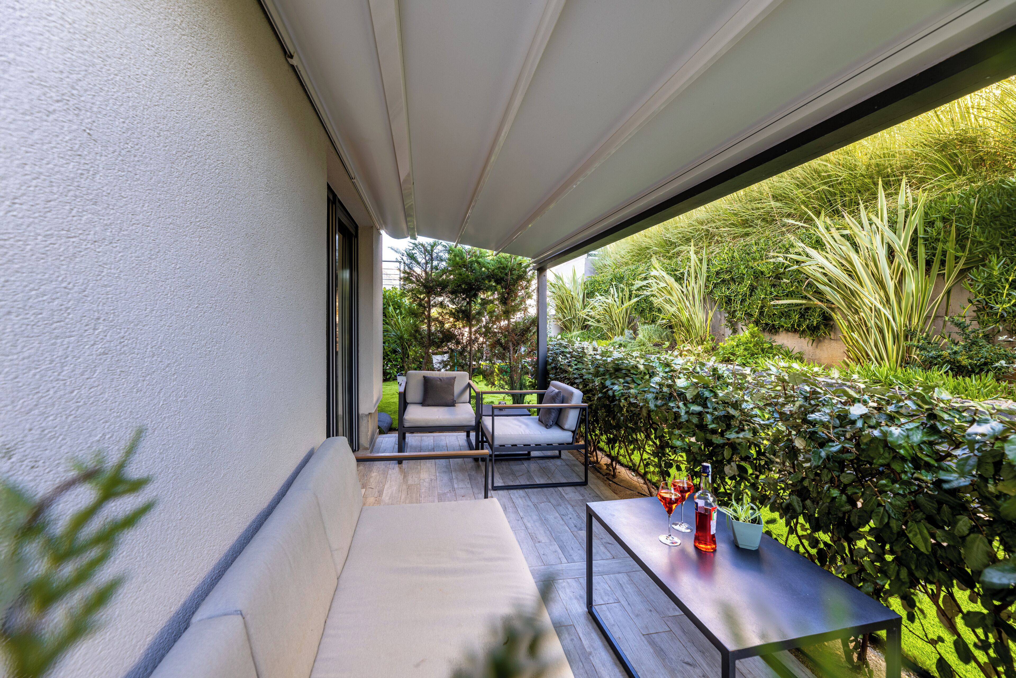An outdoor patio with a sofa, chairs, and a table with drinks.