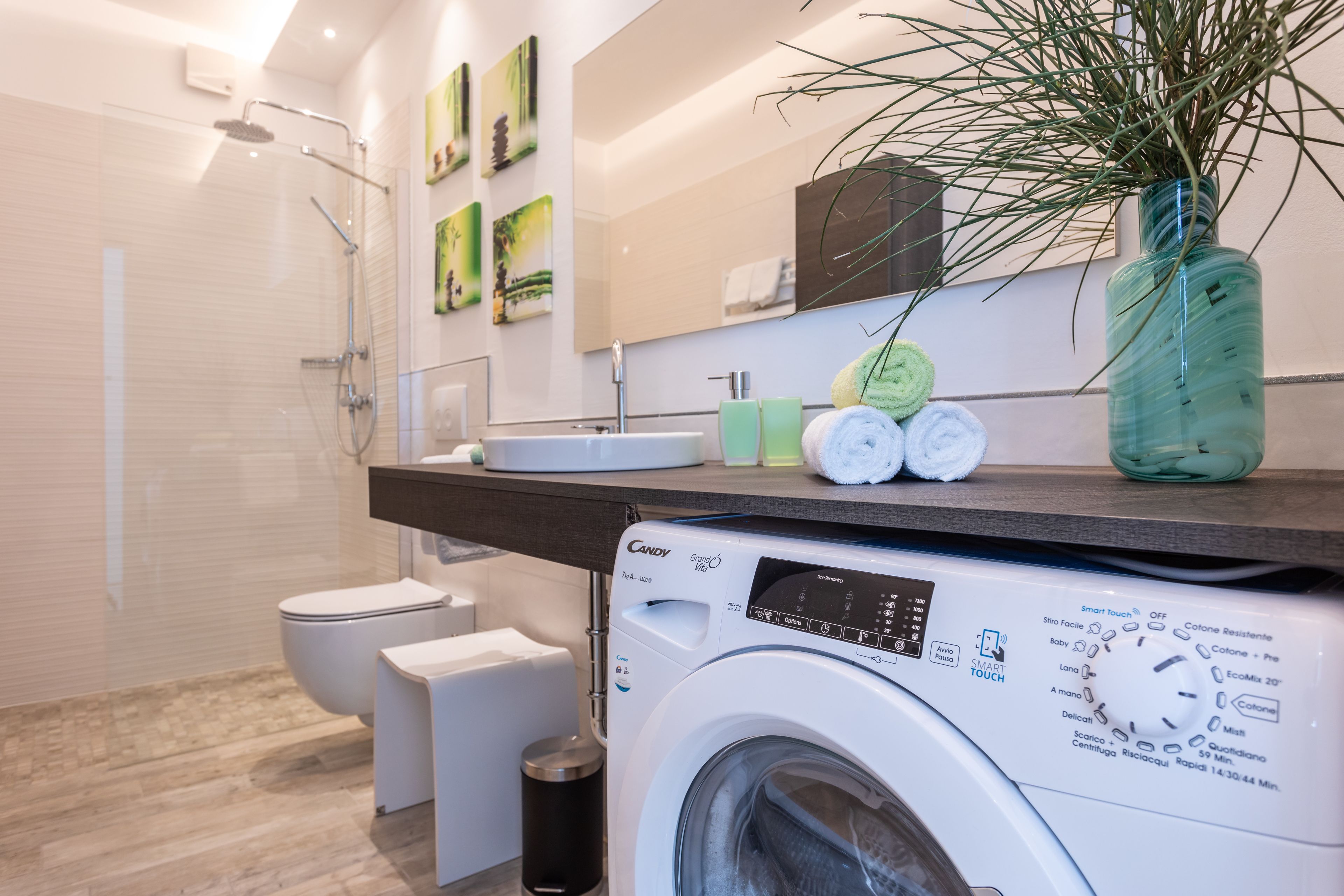 A modern bathroom with a built-in washing machine, a toilet, and a shower.