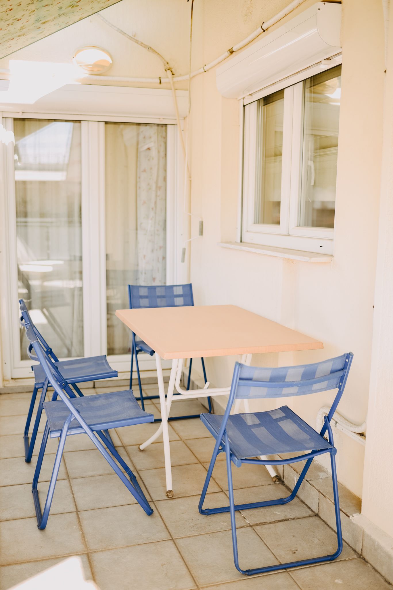 A small, enclosed patio area with a table and four blue chairs.