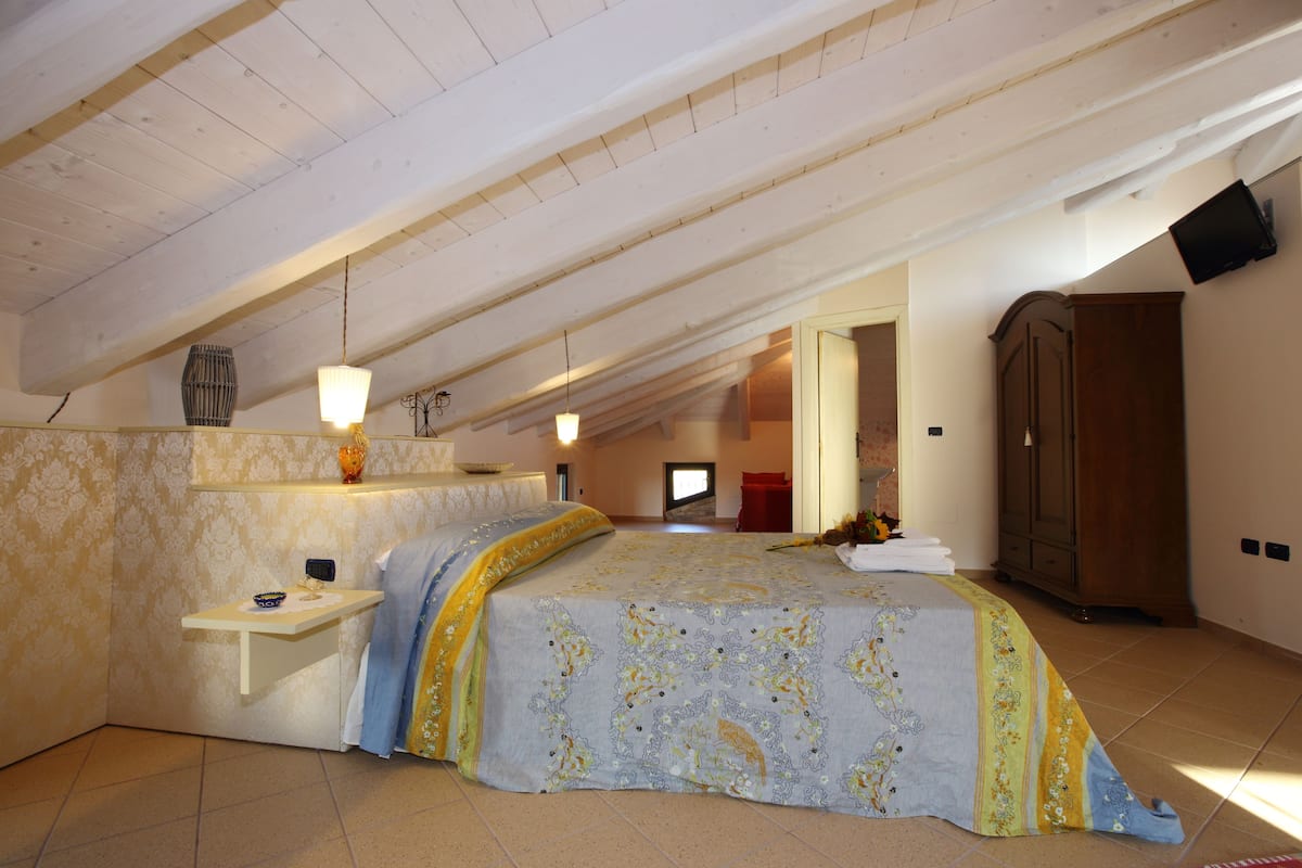 Un dormitorio con una cama grande, una mesita pequeña y un armario.