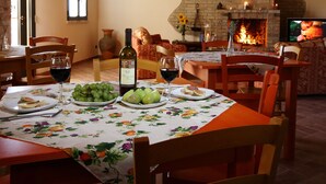 A dining area with a fireplace, wooden beams, and a table set with plates of food and wine.