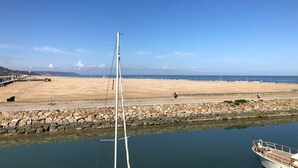 Une plage avec une digue rocheuse, une eau calme et une côte visible au loin.