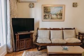 Departamento tradicional, 1 cama King size y sofá cama, balcón, vista a la ciudad | Área de sala de estar | Televisión de pantalla plana 