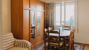 A dining area with a wooden table and chairs, a striped sofa, and a large wooden cabinet. - Best House Attiki Metro (Athens)