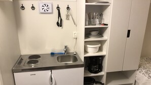 Une petite cuisine équipée d’une cuisinière, d’un évier et d’étagères de rangement.