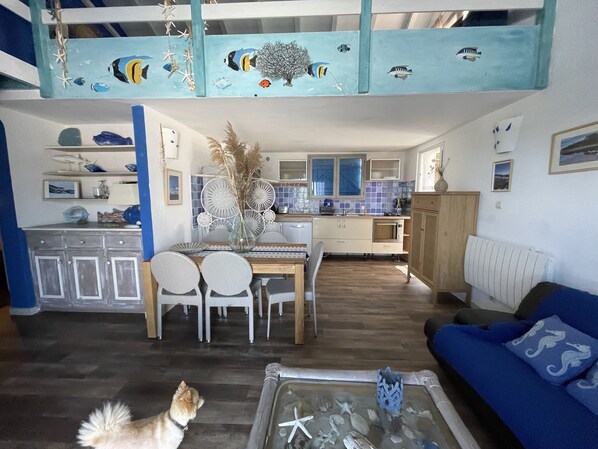 A spacious living area with a high ceiling, a dining table with chairs, a sofa, and a dog. - Residence Fium del Cavo (Zonza)