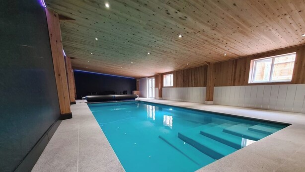 Una piscina interior con suelo de baldosas y paredes de madera.