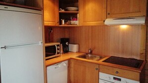 Une cuisine compacte dotée de meubles en bois, d’un four à micro-ondes, d’un grille-pain, d’un évier et d’un lave-vaisselle.