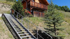 Une cabane en bois dotée d’un balcon, d’un escalier menant à ce balcon et d’un ciel bleu azur.