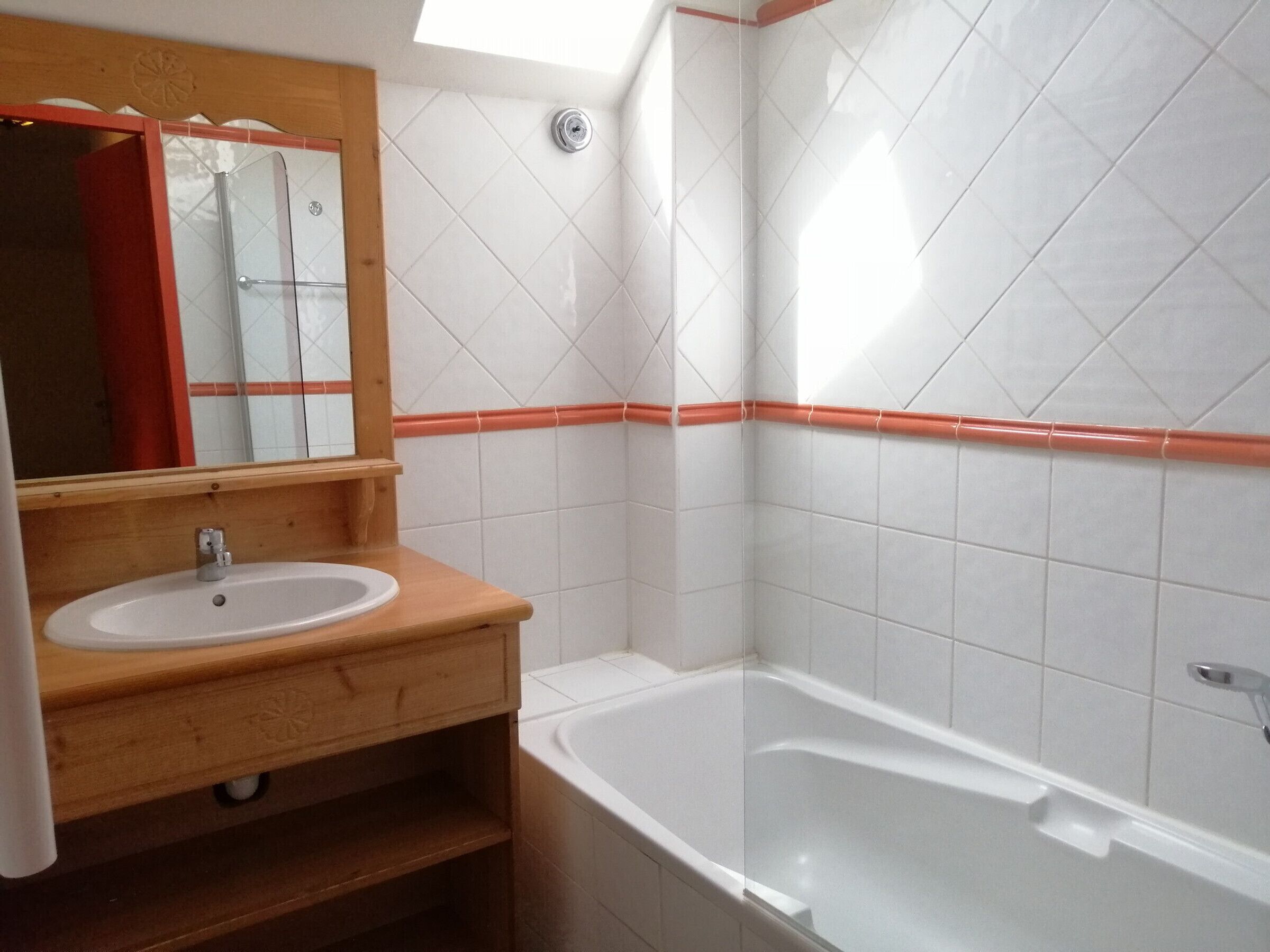 A bathroom with a wooden vanity, white sink, and a bathtub.