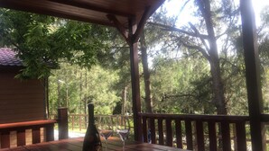 A wooden deck with a table, a bottle, and two wine glasses.