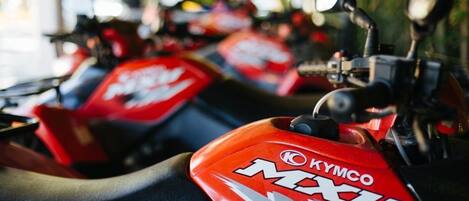 A row of red motorcycles with the brand "KYMCO MXU" visible on the fuel tanks.