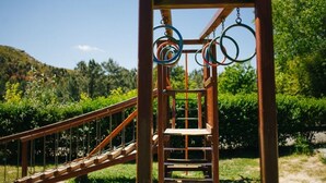 A wooden playground structure with a slide and rings for climbing.