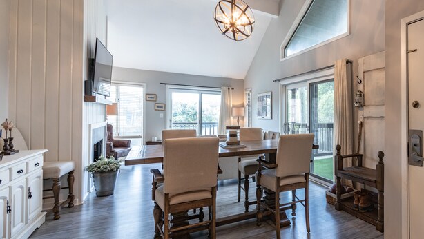 A spacious dining area with a long wooden table, several chairs, and a hanging light fixture.