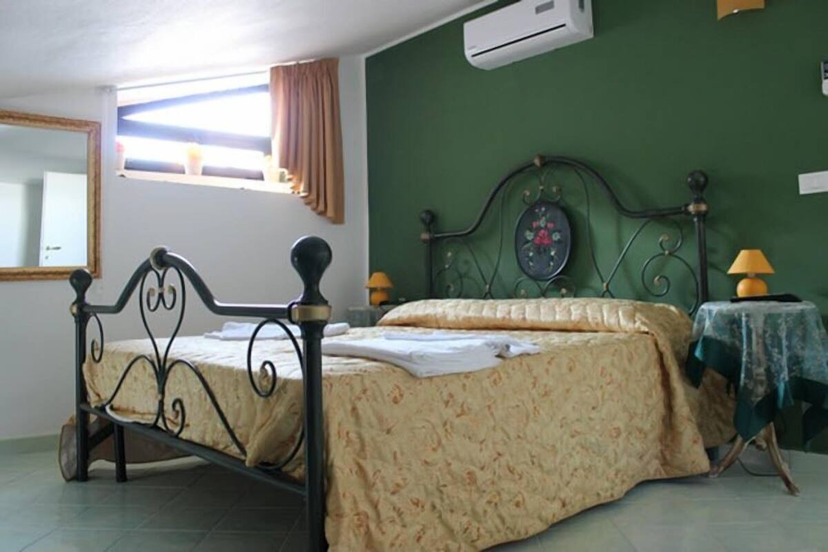 A bedroom with a bed, a nightstand, a lamp, and a window with curtains.