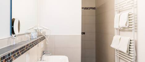 A modern bathroom with a white sink, a mirror, and a towel rack.