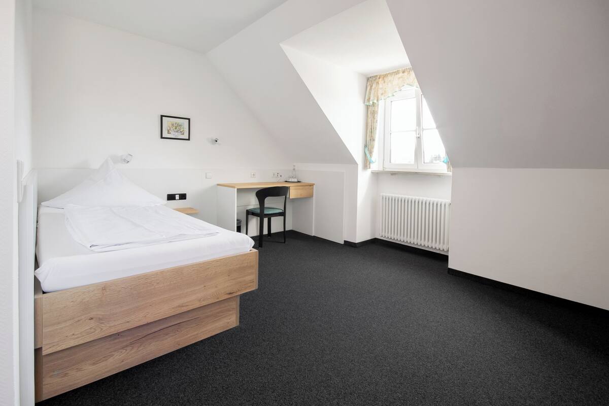 A bedroom with a bed, a desk, and a chair.