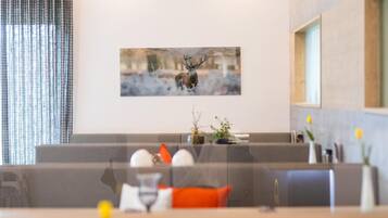 Um hall de hotel moderno com uma grande pintura de um veado na parede, área de estar com uma mesa e uma janela com vista.