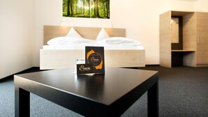 Ein Hotelzimmer mit Bett, Tisch mit einem Schild und Blick auf einen Wald.